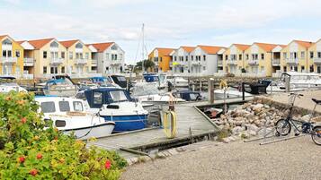 A marina with boats docked, a wooden pier, and row houses in the background.