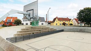 Un terrain de basket en plein air doté d’une structure métallique, de marches en béton et d’une clôture.