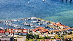Un port de plaisance avec des bateaux amarrés, un pont en arrière-plan et une ville aux bâtiments aux couleurs vives.