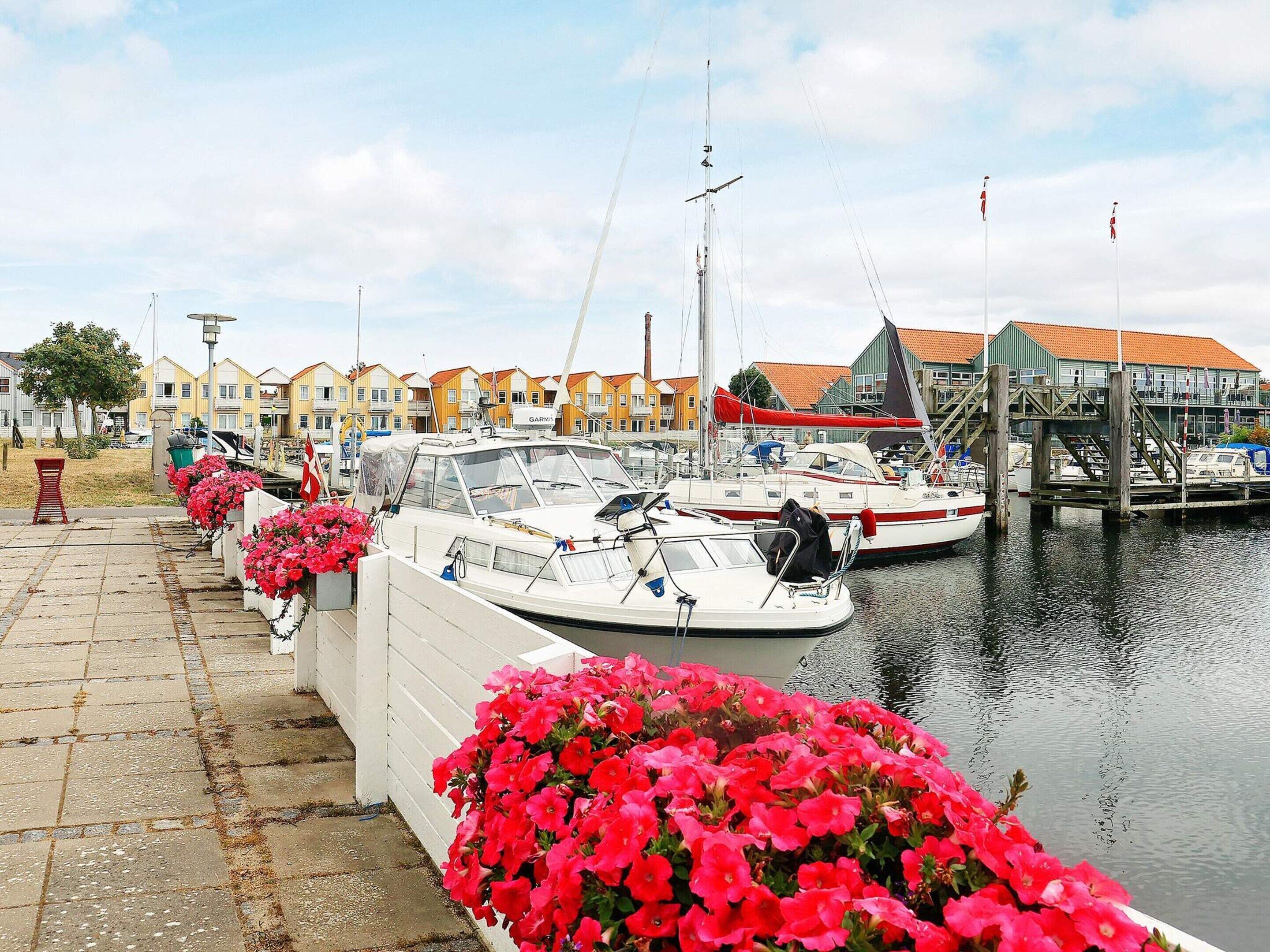 A marina with boats docked, a waterfront walkway, and colorful buildings in the background.