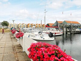 Un puerto deportivo con barcos amarrados, un paseo marítimo y edificios coloridos al fondo.