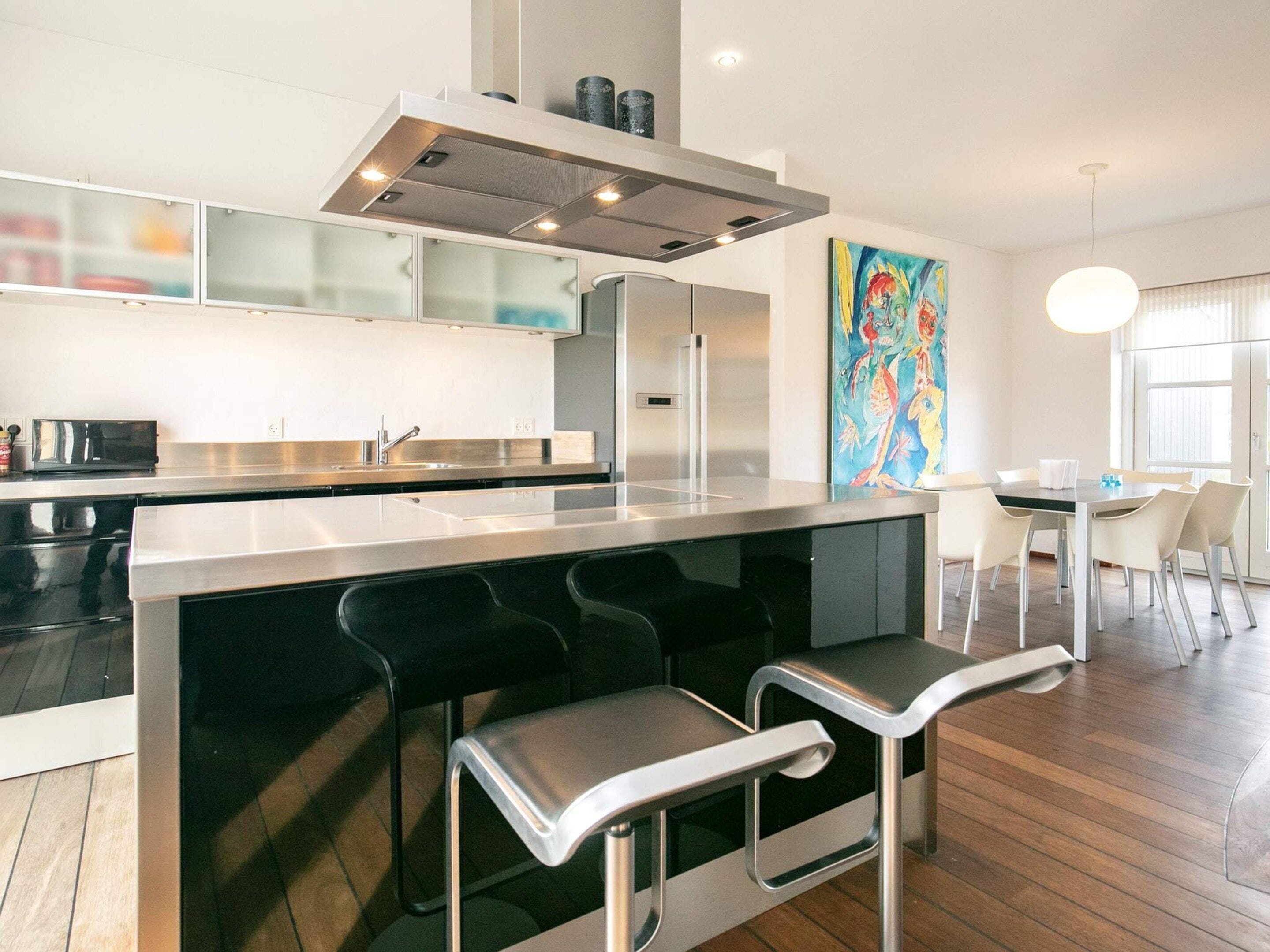 Une cuisine moderne dotée d’un îlot central, de tabourets de bar et d’un coin repas avec une table et des chaises.
