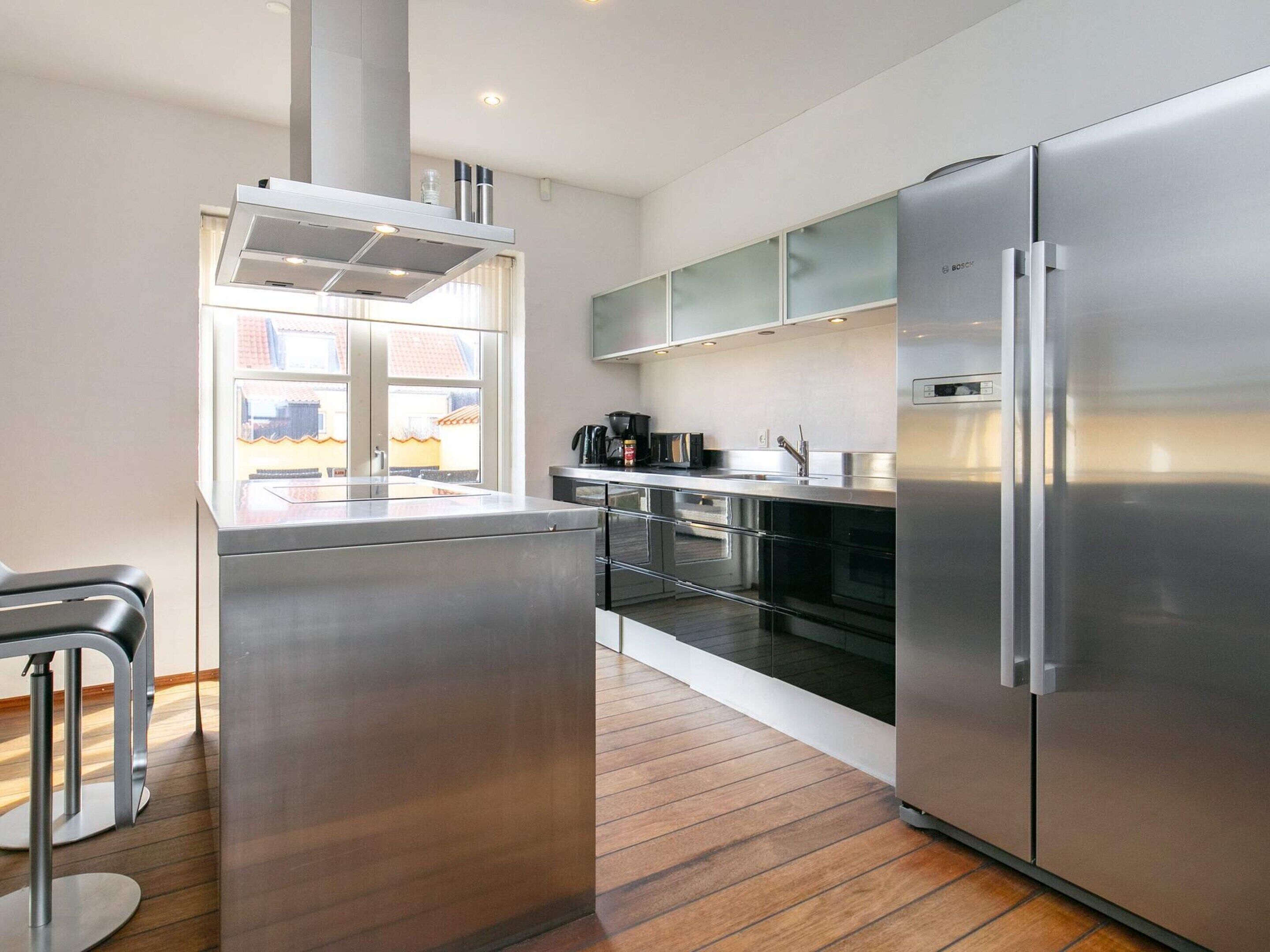 Una cocina moderna con electrodomésticos de acero inoxidable, una isla central y un ventanal con vistas a una zona residencial.