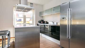 Una cocina moderna con electrodomésticos de acero inoxidable, una isla central y un ventanal con vistas a una zona residencial.