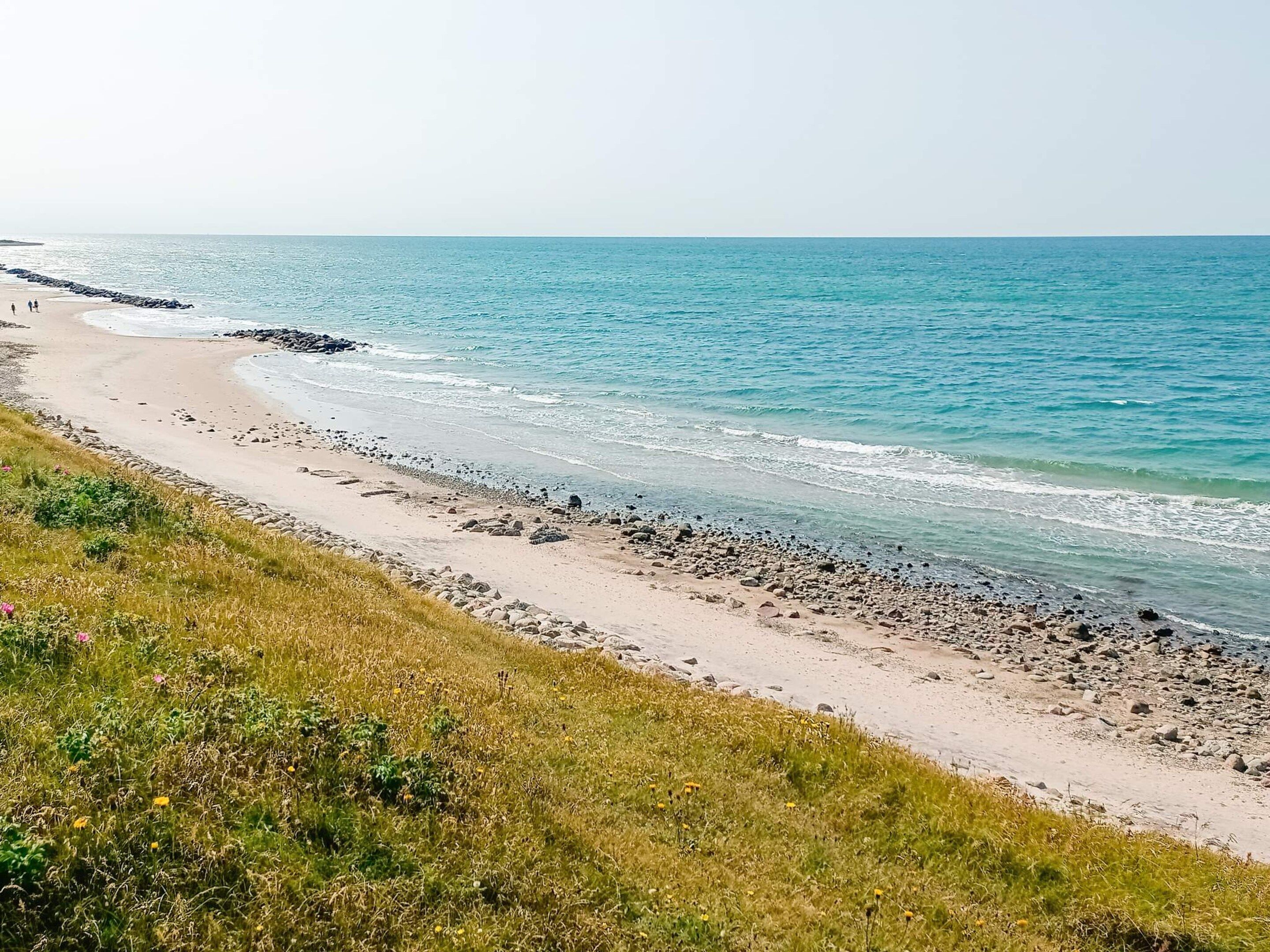 Egy sziklás parttal és füves területekkel rendelkező strand.