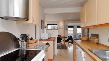 A modern kitchen with a stove, microwave, and dishwasher. There is a dining area with a table and chairs.