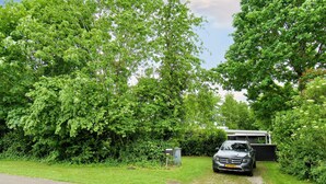 A car parked in a driveway with a garage and lush greenery surrounding the property. - 5 Person Holiday Home in Gilleleje (Gilleleje)