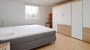 A bedroom with a bed, a window, a wardrobe, and a radiator. - 5 Person Holiday Home in Gilleleje (Gilleleje)