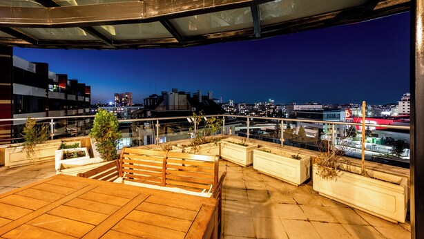 A rooftop terrace with a view of a city skyline at dusk.