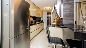 A modern kitchen with stainless steel appliances, a black bar counter, and a seating area with chairs.