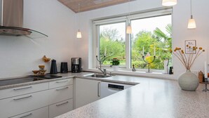 A modern kitchen with a large window, granite countertops, and stainless steel appliances.
