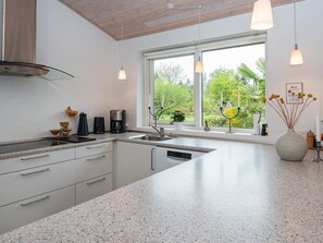 A modern kitchen with a large window, granite countertops, and stainless steel appliances. - 6 Person Holiday Home in Grenaa (Grenaa)
