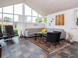 A modern living room with a grey sofa, black armchairs, a patterned rug, and large windows. - 6 Person Holiday Home in Grenaa (Grenaa)