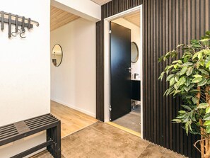 A hallway with a bench, a coat rack, and a door leading to a bathroom. - 4 Star Holiday Home in Albaek (Aalbaek)