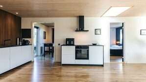 A modern kitchen with a central island, wooden flooring, and a skylight. - 4 Star Holiday Home in Albaek (Aalbaek)