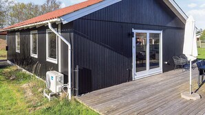A black metal building with a red roof, a wooden deck, and a sliding glass door. - 4 Star Holiday Home in Albaek (Aalbaek)