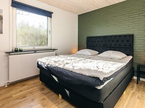 A bedroom with a bed, a window, a radiator, and a brick wall.