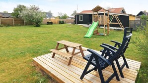 A backyard with a wooden deck, picnic table, and chairs. - 4 Star Holiday Home in Albaek (Aalbaek)
