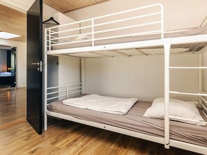 Un letto a castello con una scrivania estraibile, una porta e un pavimento in legno.
