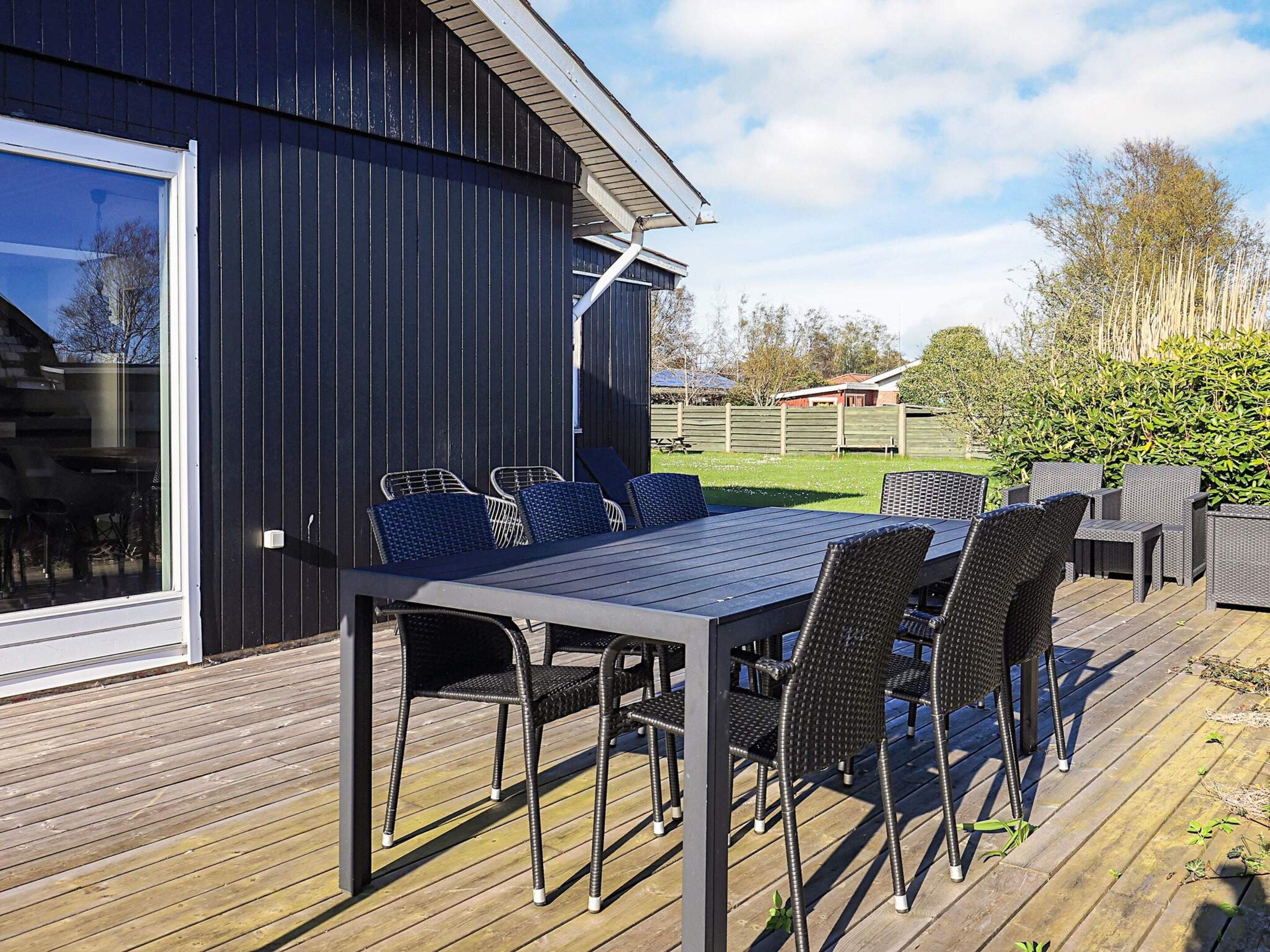 A deck with a table and chairs, a wooden deck, and a building with a dark facade.