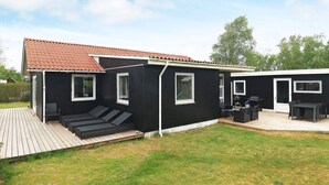 A modern black house with a red-tiled roof, a deck, and a patio area with outdoor furniture. - 4 Star Holiday Home in Albaek (Aalbaek)