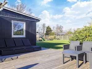 A deck with outdoor furniture, a wooden fence, and a playground in the background.