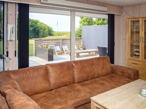 A brown leather sofa in a room with a wooden cabinet and a table.