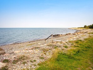 A rocky shoreline with a wooden structure, likely a bench or seating area, overlooking a calm body of water. - 6 Person Holiday Home in Hurup Thy (Hurup Thy)