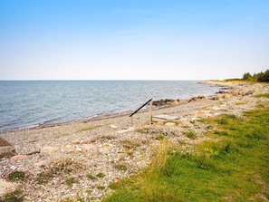 A rocky shoreline with a wooden structure, possibly a bench or seating area, overlooking calm waters. - 6 Person Holiday Home in Hurup Thy (Hurup Thy)