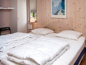 A bedroom with a wooden headboard, a bed with white bedding, a chair, and a window with a view of greenery. - 6 Person Holiday Home in Hurup Thy (Hurup Thy)