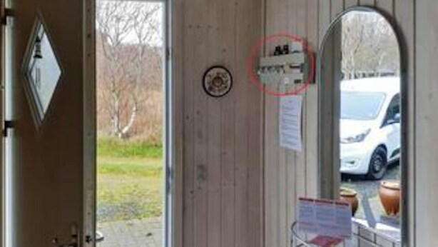 A door with a circular sign, a small window, and a view of a parked car outside. - 6 Person Holiday Home in Hurup Thy (Hurup Thy)