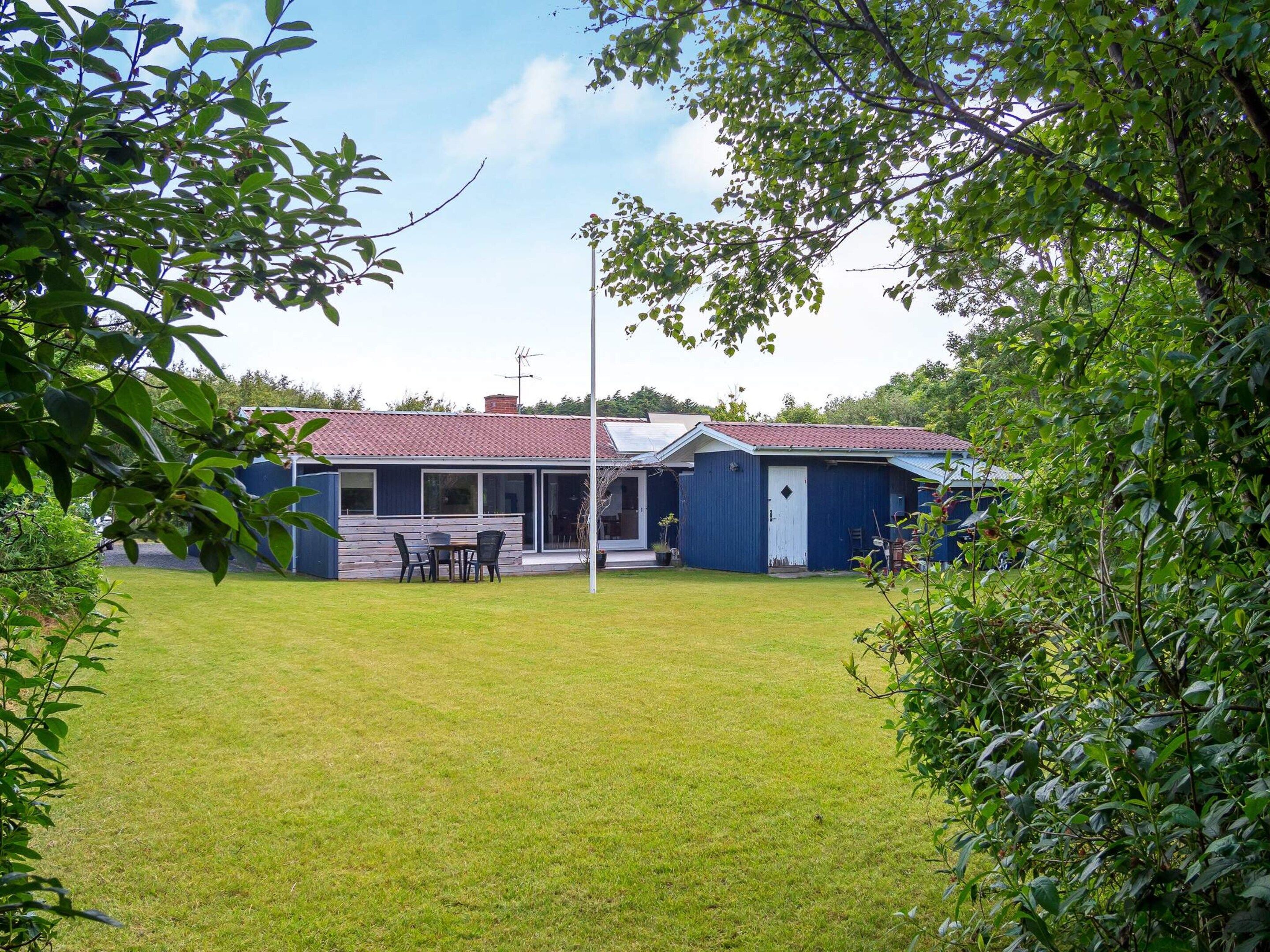 Ein Haus mit rotem Dach, einer überdachten Terrasse und einem Rasen.