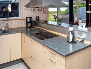 A modern kitchen with a built-in stove, a coffee maker, and a kettle.