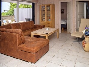 Un salon avec un canapé marron, une table basse en bois et un meuble avec des portes en verre.