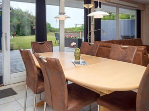 A dining area with a wooden table and brown upholstered chairs, large windows, and hanging pendant lights. - 6 Person Holiday Home in Hurup Thy (Hurup Thy)