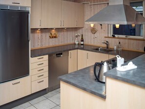 A modern kitchen with a stainless steel refrigerator, wooden cabinets, a built-in dishwasher, and a large island with a kettle and a coffee maker. - 6 Person Holiday Home in Hurup Thy (Hurup Thy)