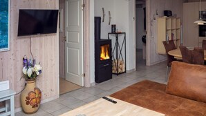 Ein Wohnzimmer mit einer Couch, einem Fernseher, einem Kamin und einer Blumenvase.