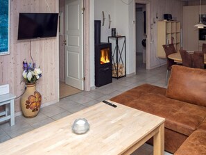 A living room with a sofa, a TV, a fireplace, and a vase with flowers. - 6 Person Holiday Home in Hurup Thy (Hurup Thy)