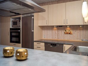 A modern kitchen with stainless steel appliances, wooden cabinets, and a built-in oven.