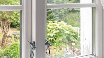 A window with a view of a garden, a tree, and outdoor furniture.