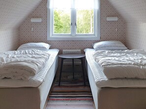 A small, cozy room with two single beds, a small table, and a window with a view of trees. - 8 Person Holiday Home in Annerstad (Annerstad)