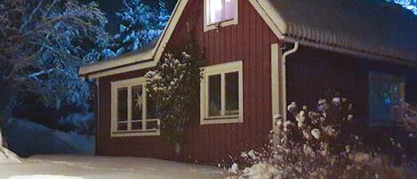A red wooden house with a gabled roof and a single window visible.