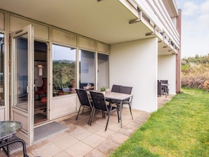 A patio with a table and chairs, a sliding glass door, and a small garden area.