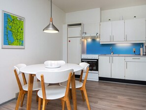 A modern kitchen with white cabinets, a blue countertop, and a dining table with chairs.