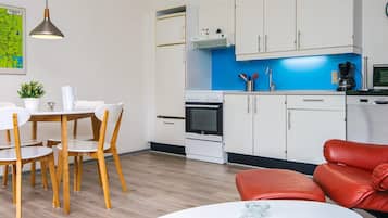Una cocina moderna con armarios blancos, horno empotrado y cafetera.