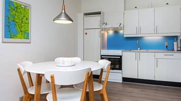A modern kitchen with white cabinets, a blue countertop, and a dining table with chairs.