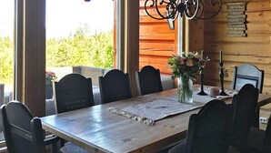Une table à manger en bois, avec six chaises, un vase rempli de fleurs et une bougie posée sur un set de table.