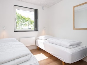 A room with two beds, a window, and a mirror.