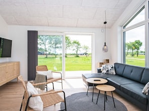 A modern living room with a sofa, two chairs, a small table, and a television.