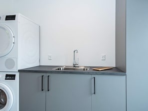 A compact kitchen with a built-in washing machine, a sink, and cabinets.